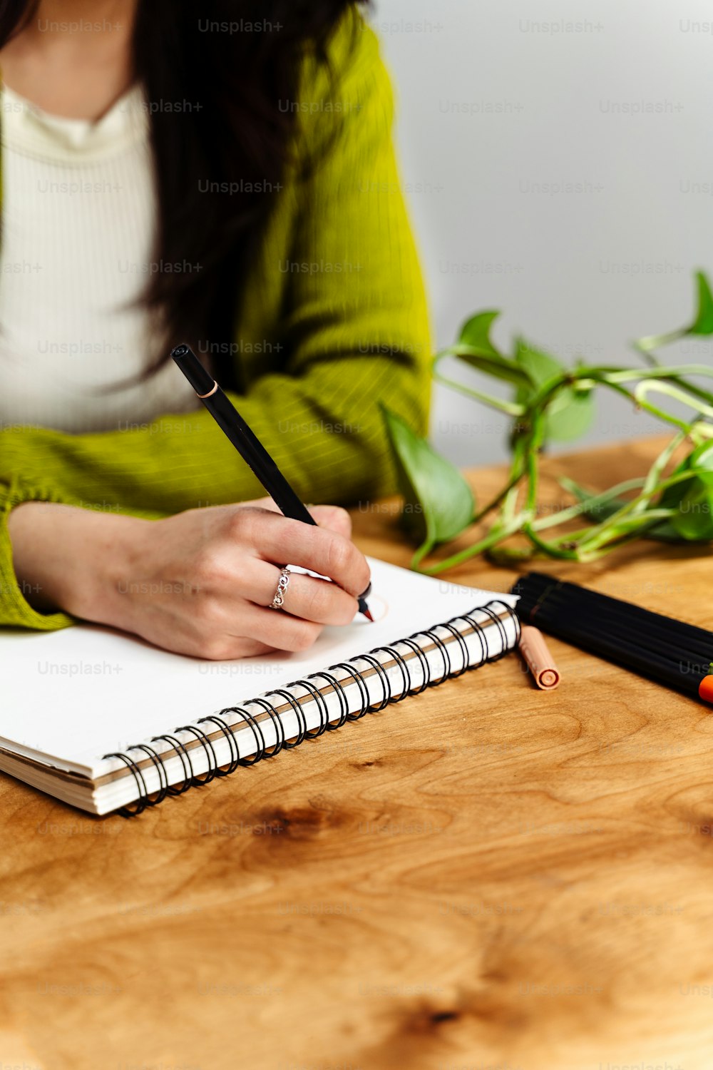 a woman sitting at a table with a notebook and pen
