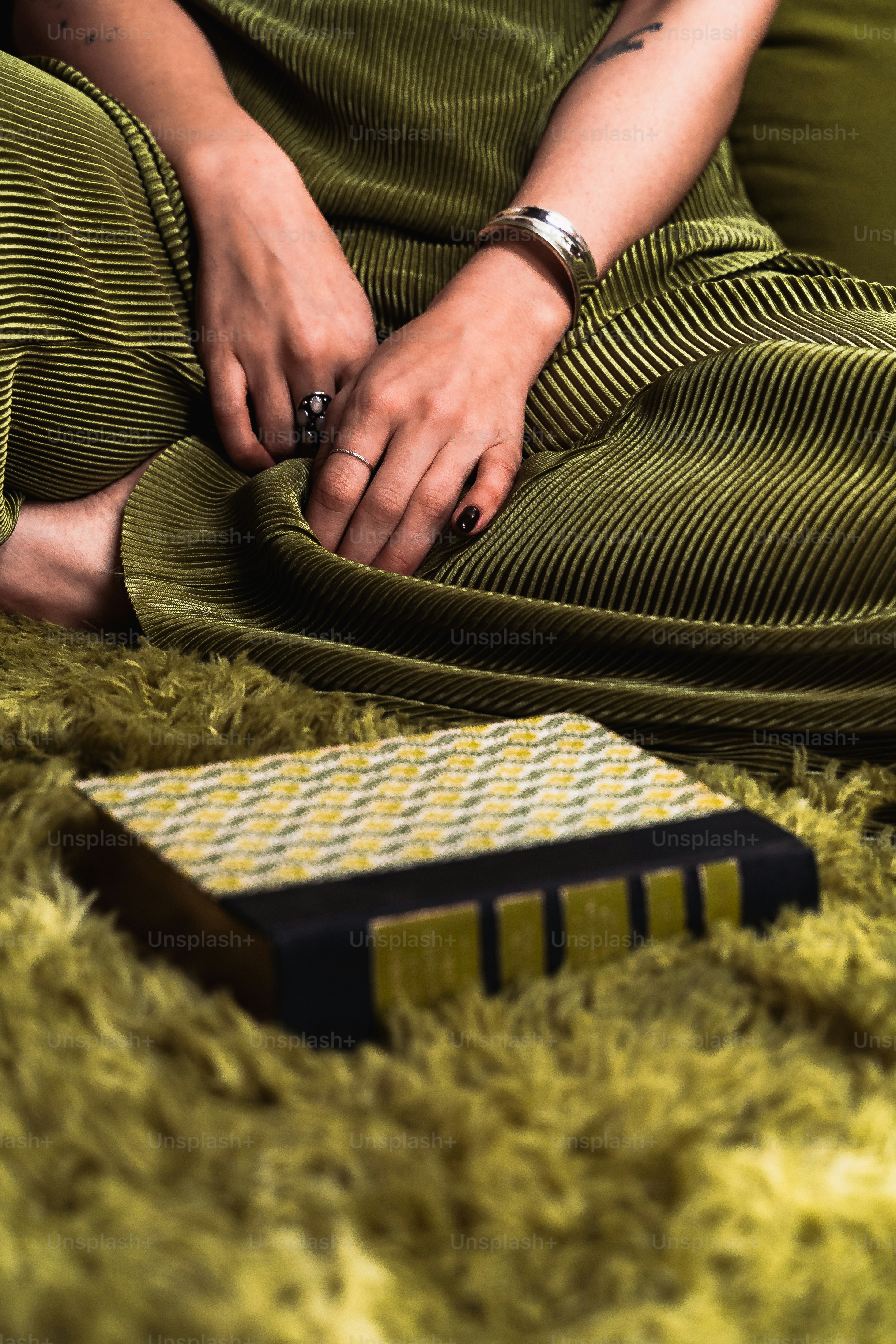 緑の絨毯の上に座り、櫛に手を添える女性