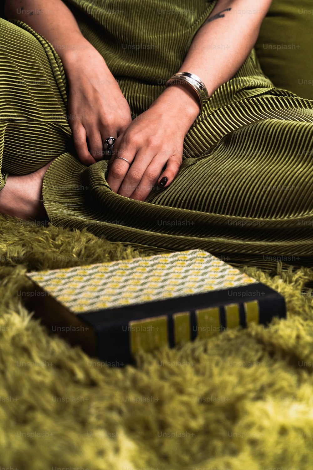a woman sitting on a green rug with her hand on a comb