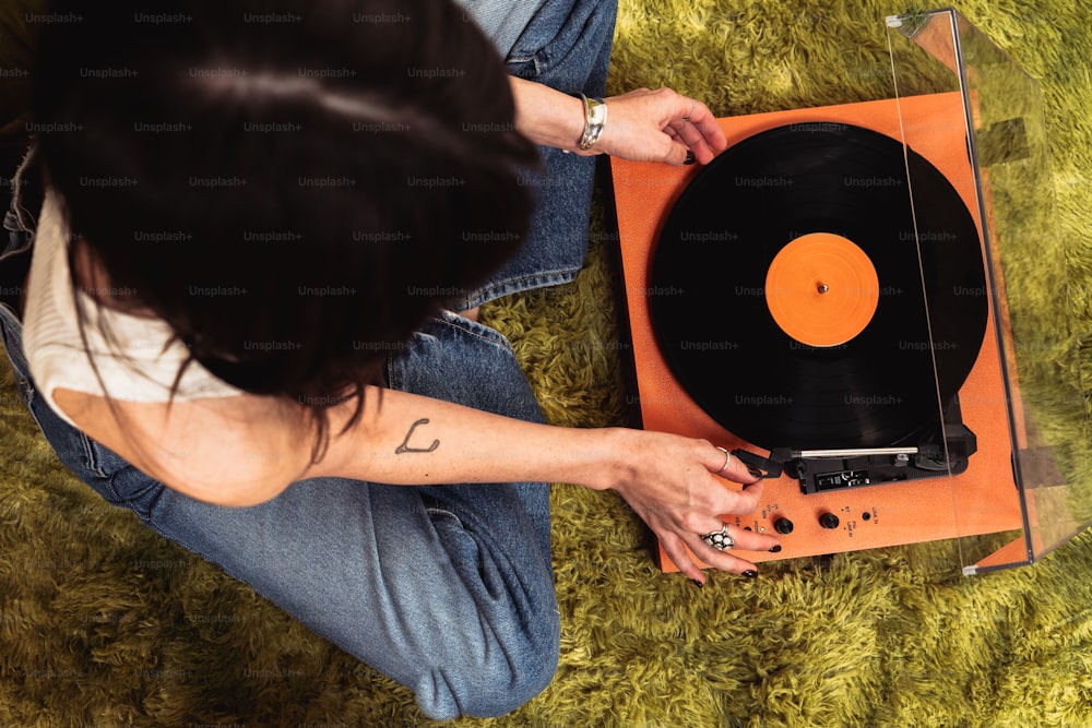 a woman sitting on the floor next to a record player