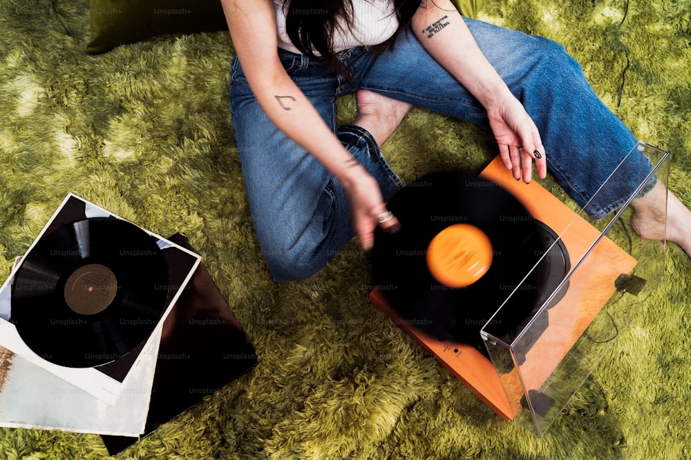uma mulher sentada no chão ao lado de um toca-discos