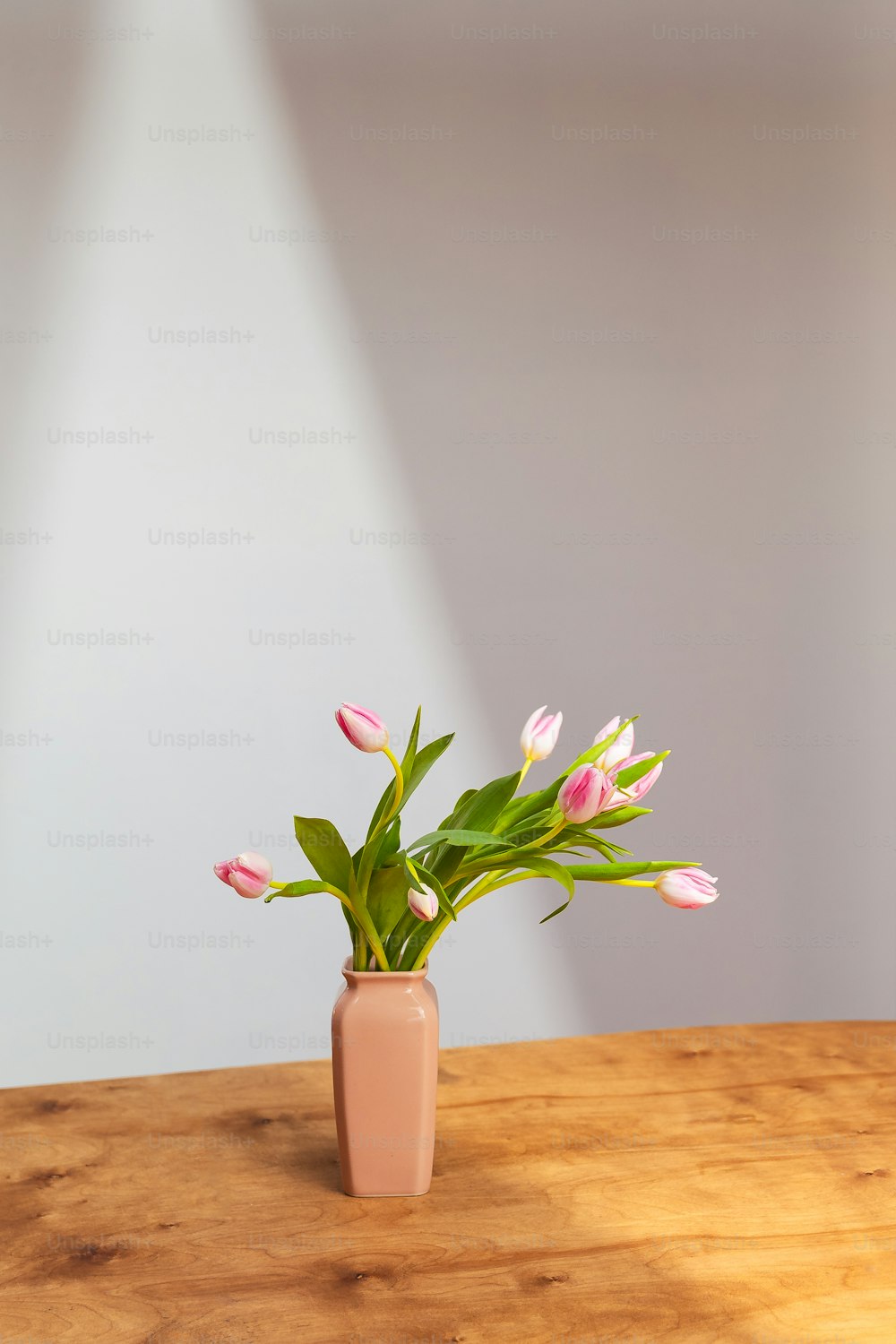 木製のテーブルの上にピンクの花を生けた花瓶