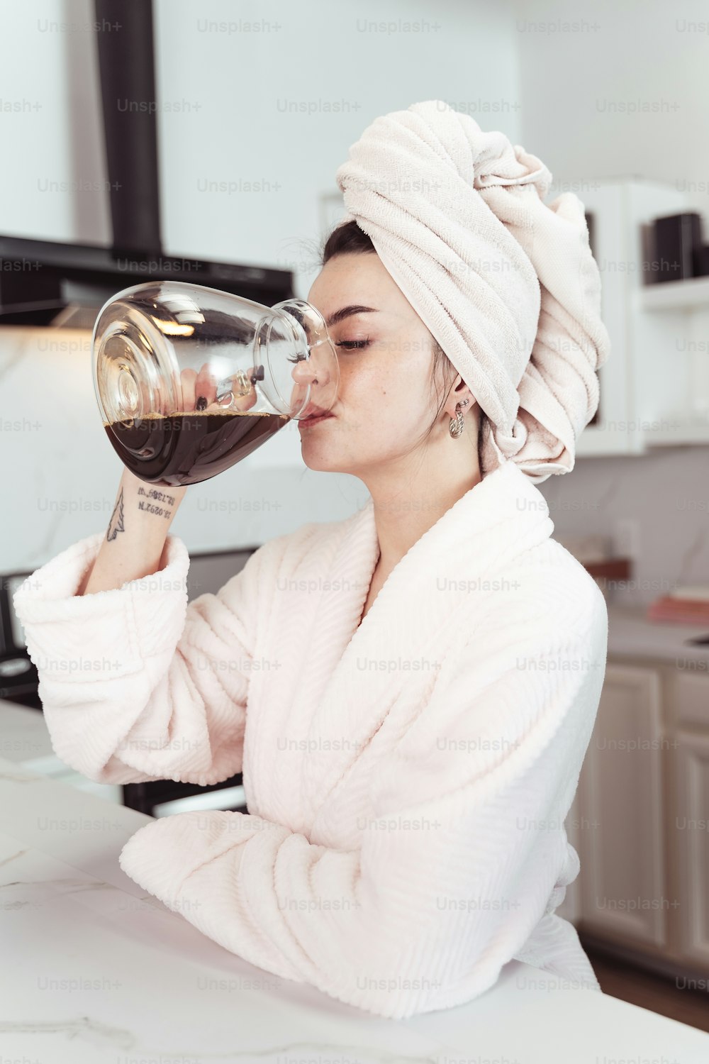 une femme avec une serviette sur la tête buvant dans un verre de vin