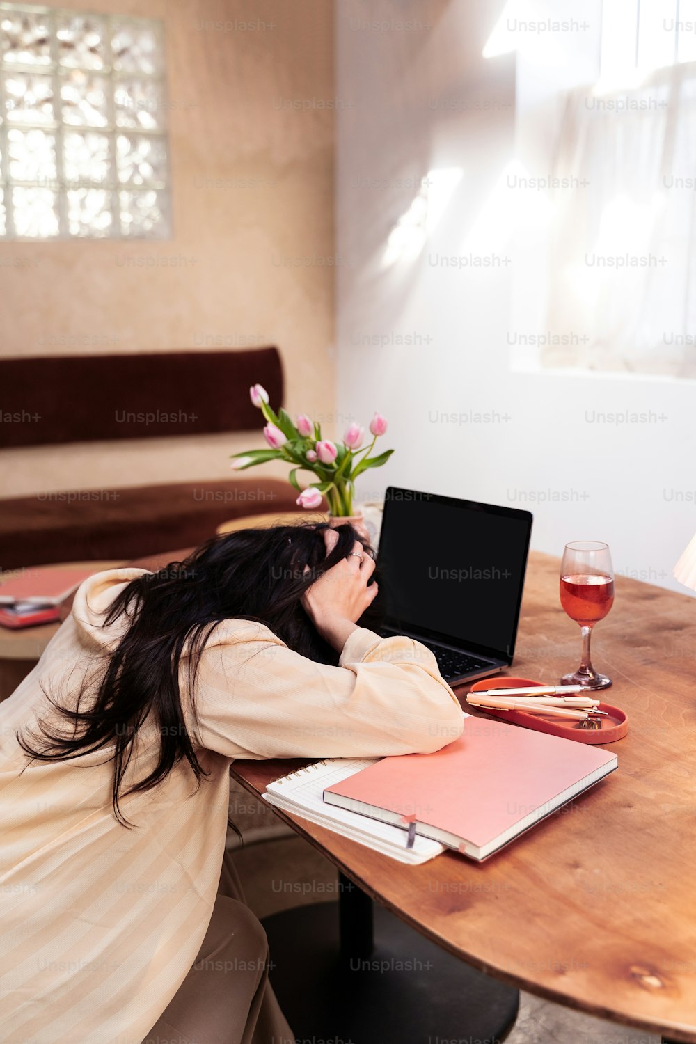 uma mulher sentada em uma mesa com um laptop e uma taça de vinho