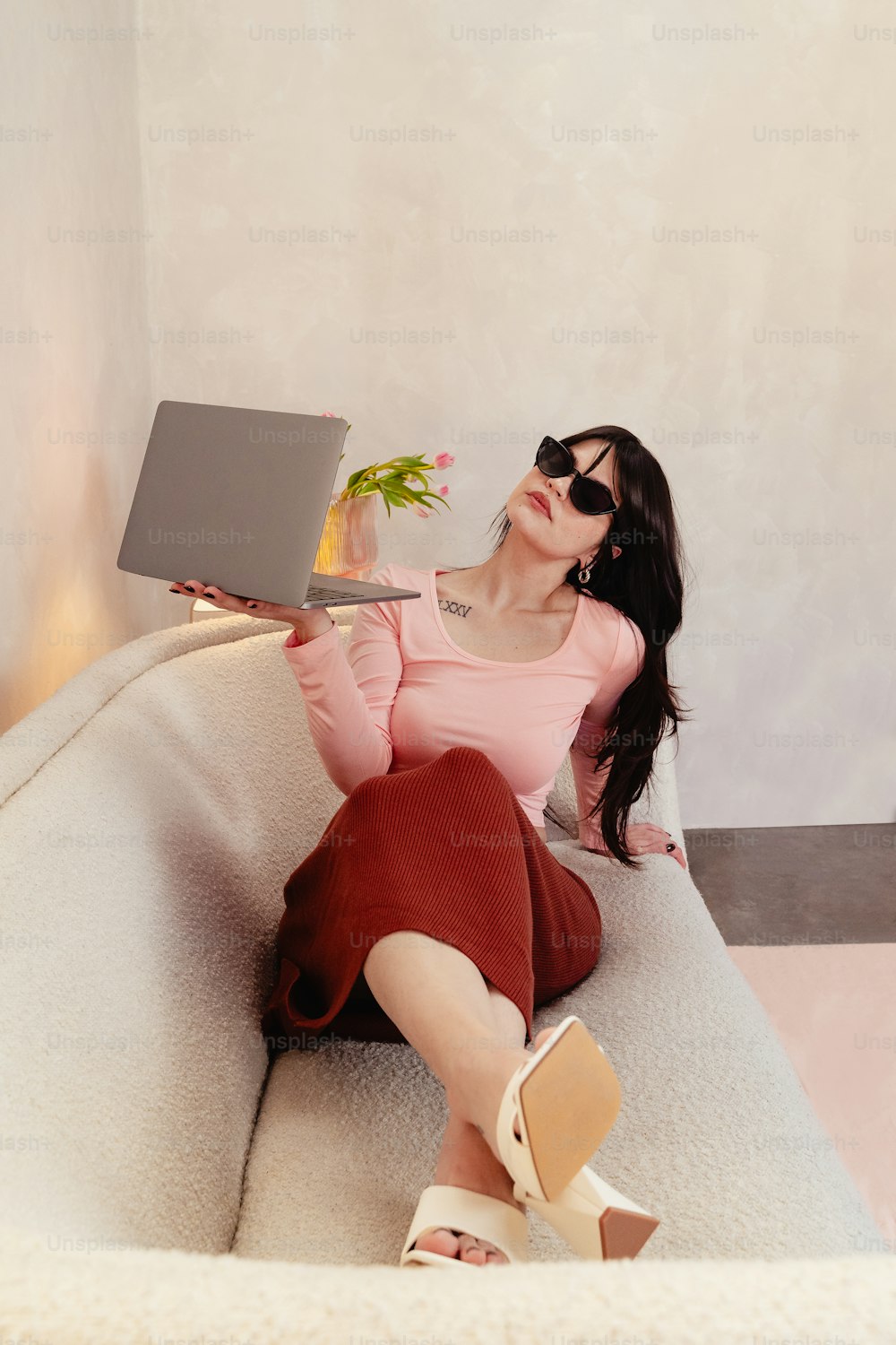 eine Frau sitzt auf einer Couch und hält einen Laptop in der Hand