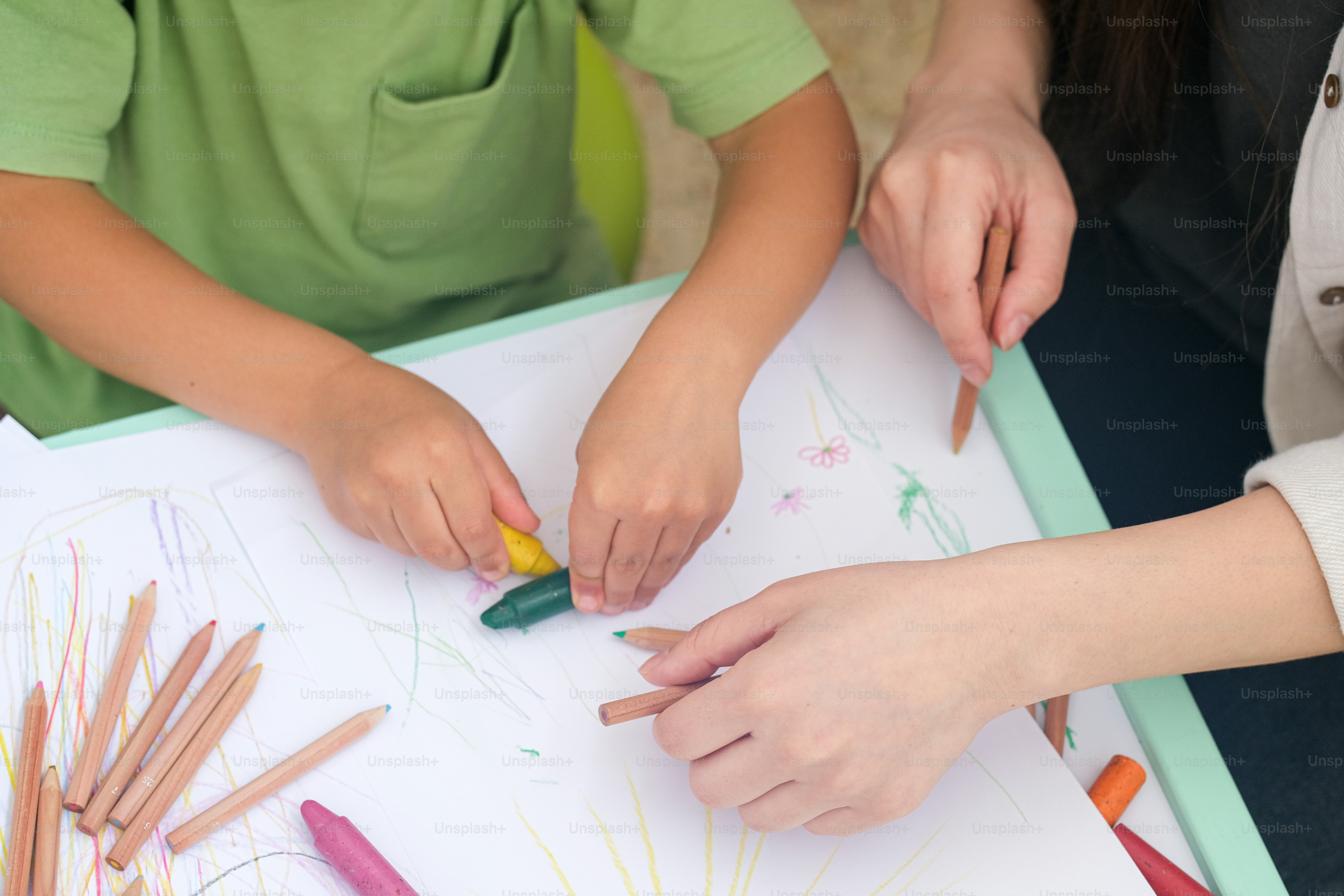 A group of children sitting at a table with crayons photo – Parenting ...