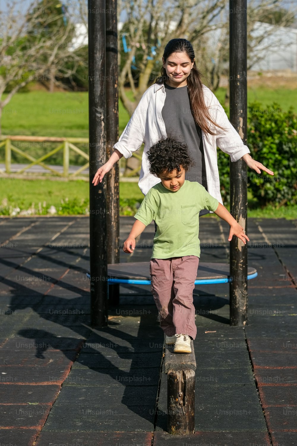 a woman standing next to a little boy on a skateboard