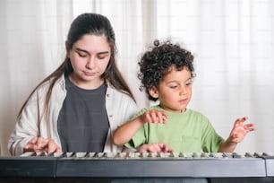 a woman and a child are playing on a keyboard