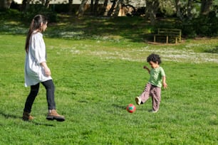 a woman and a child playing with a soccer ball
