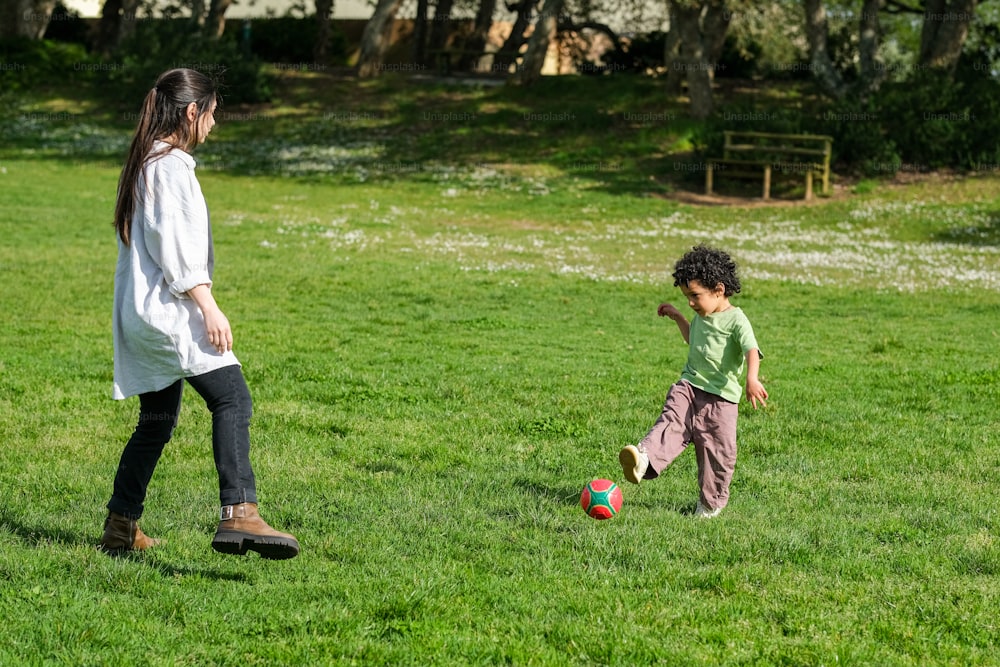 a woman and a child playing with a soccer ball