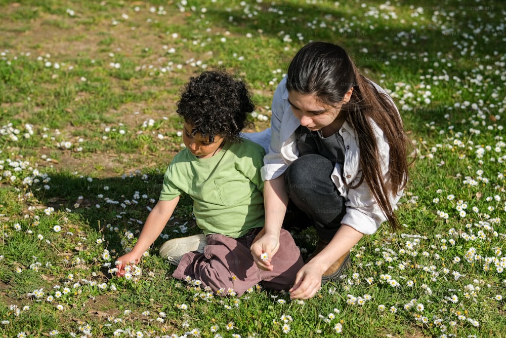 a woman kneeling down next to a child on a field of flowers