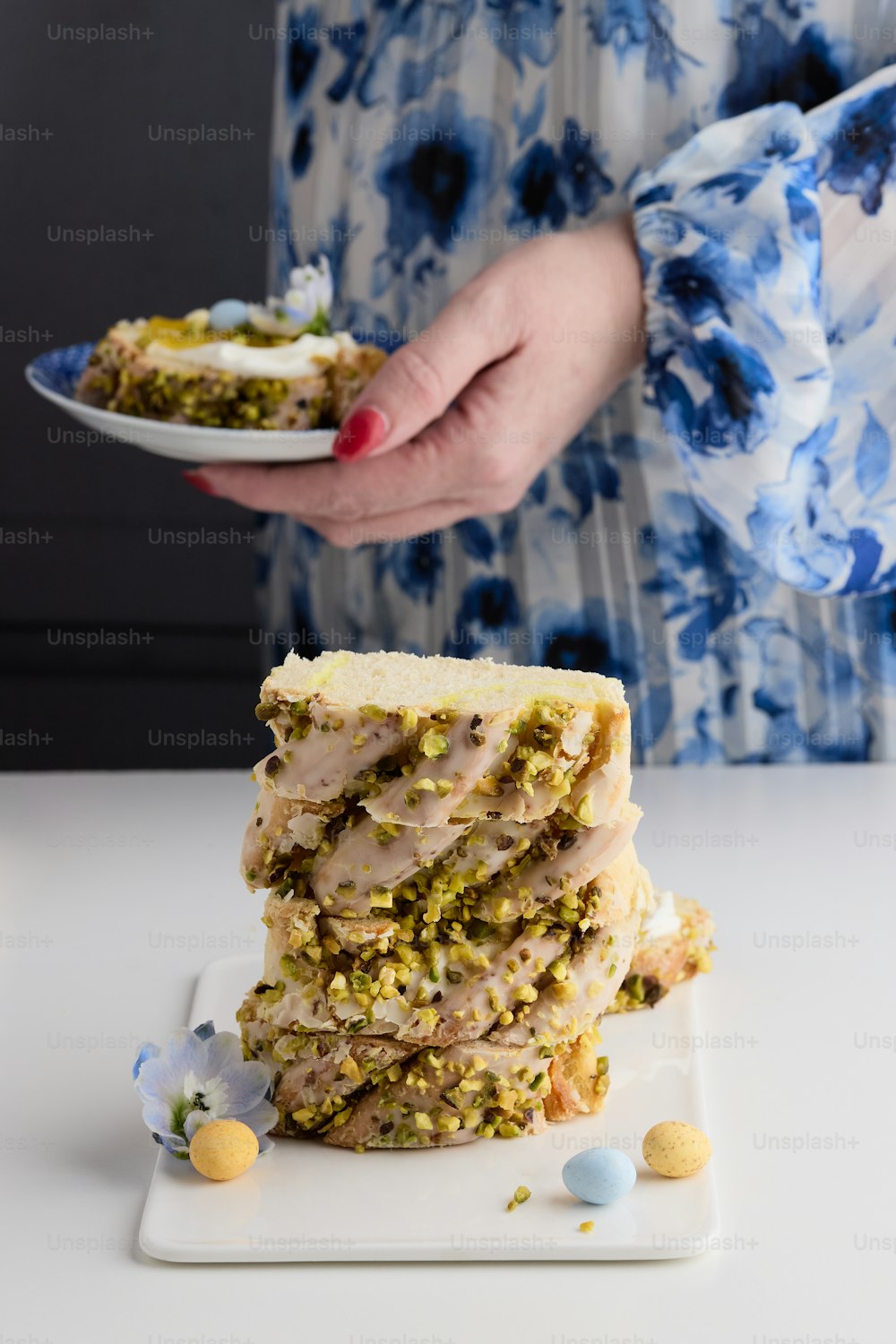 a woman holding a plate with a stack of food on it