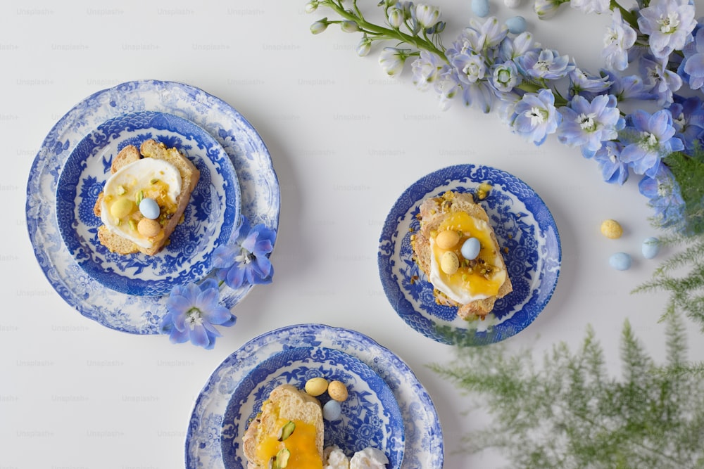 drei blaue Teller mit Essen neben Blumen