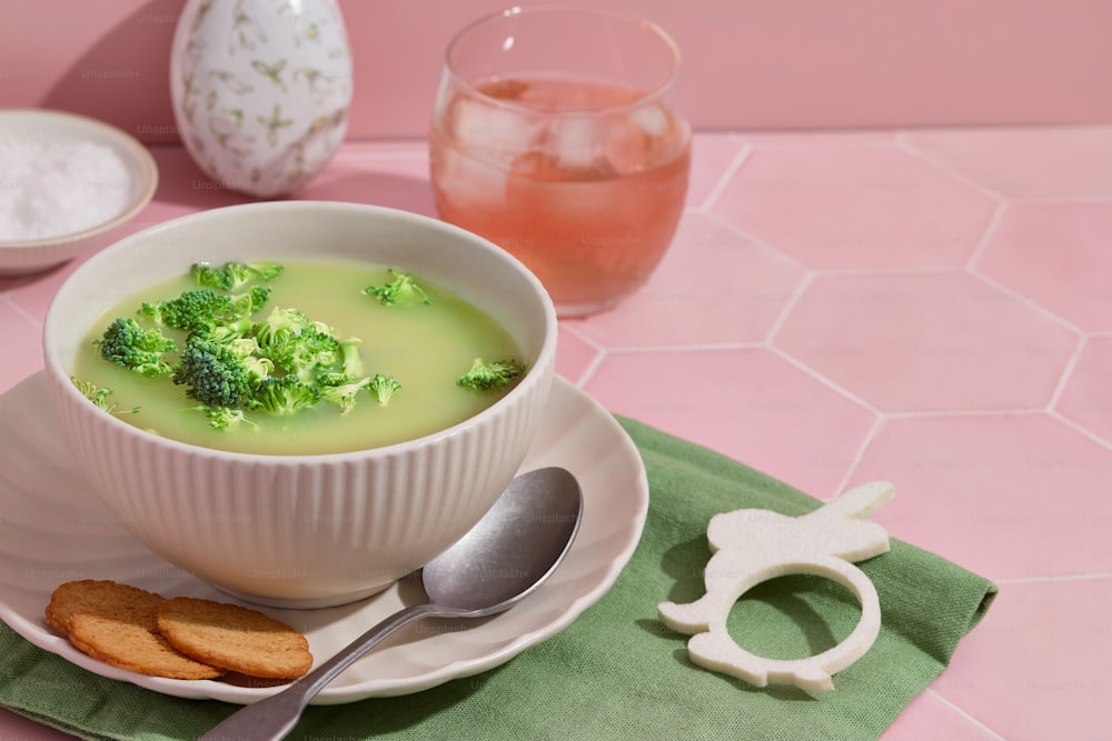 a bowl of broccoli soup on a plate with a spoon