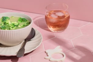 a bowl of broccoli soup next to a drink