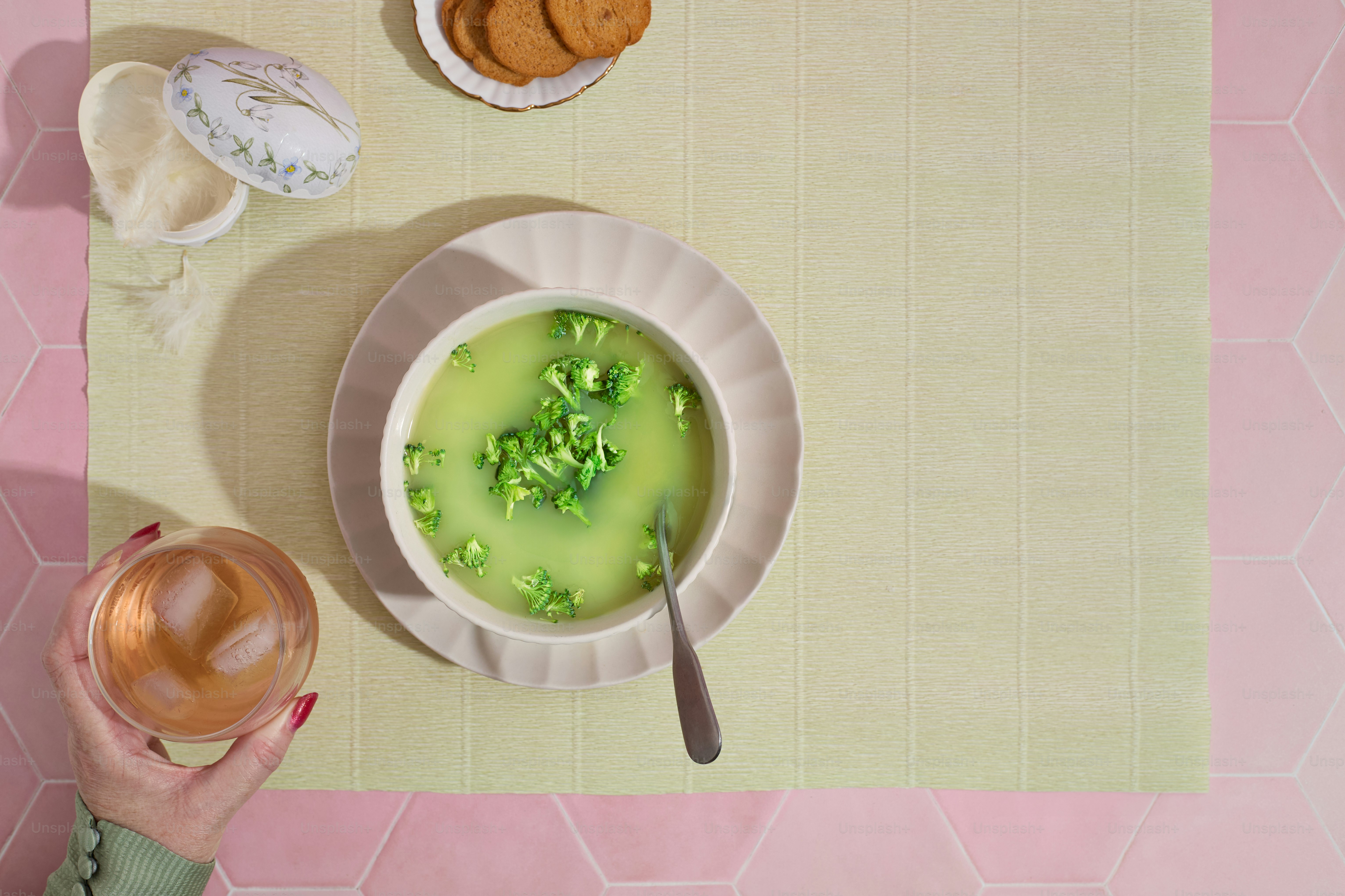 Overhead of broccoli soup on pink surface table setting Easter