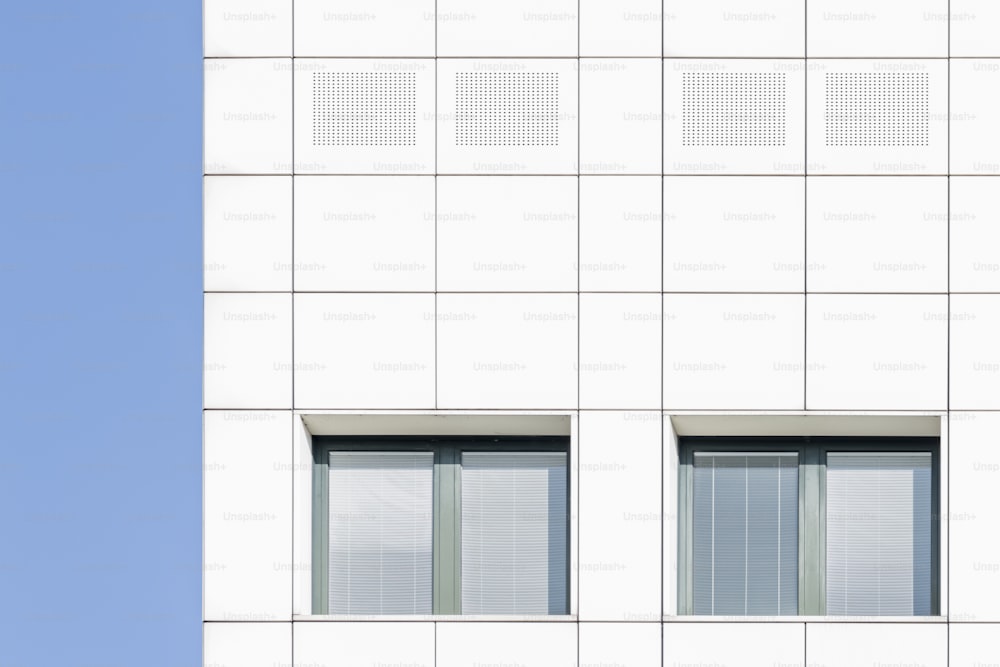 a tall white building with two windows and a clock