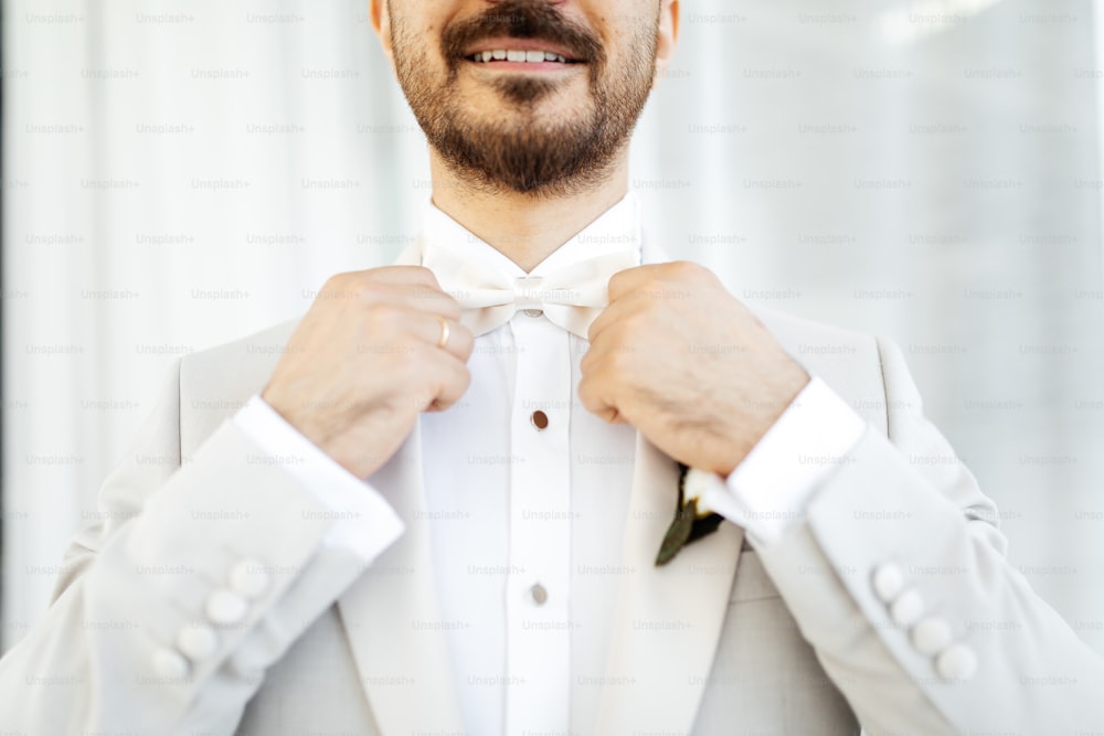 a man in a tuxedo adjusts his bow tie