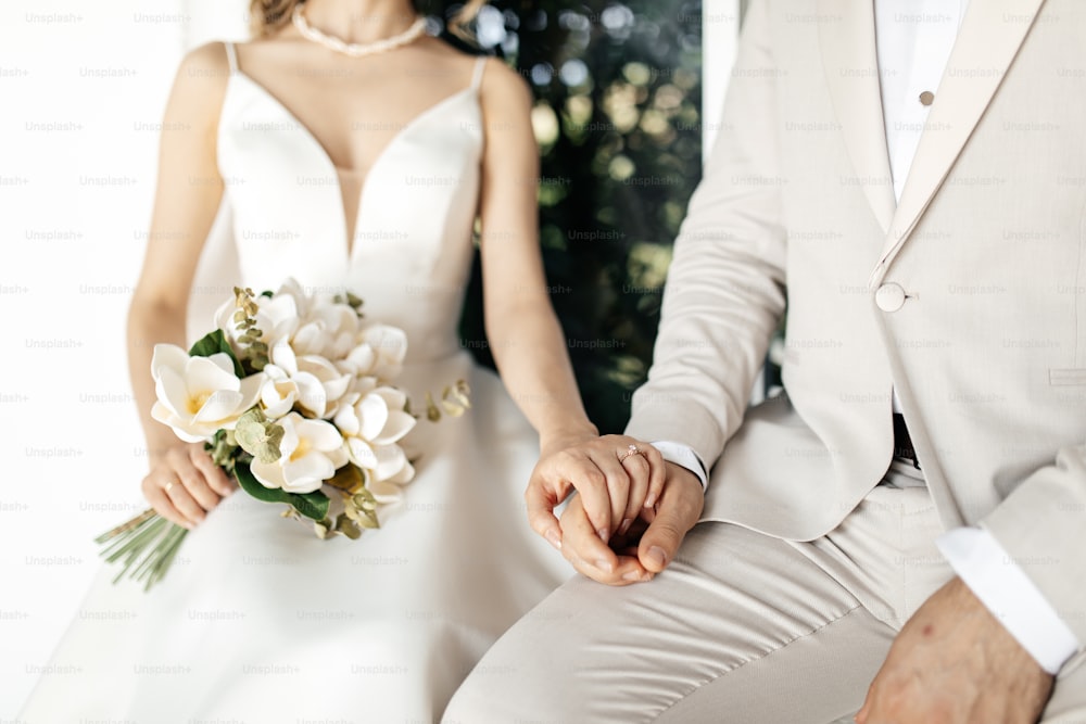 a bride and groom holding hands while sitting next to each other