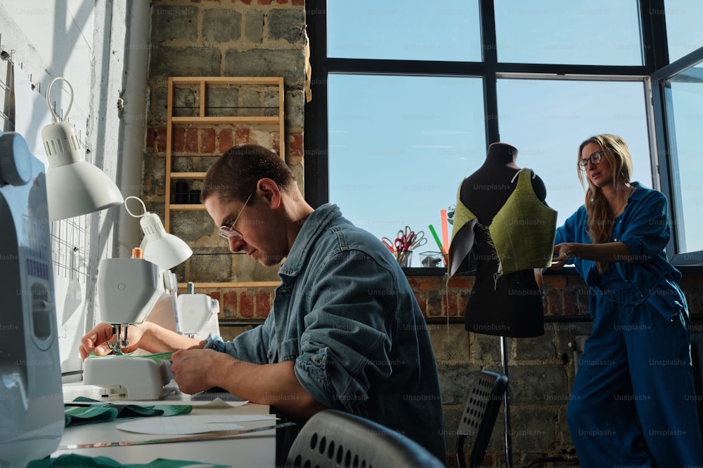 a man sitting at a table working on a piece of art