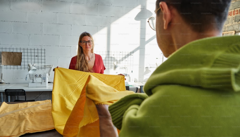 Une femme tient un tissu jaune dans une pièce