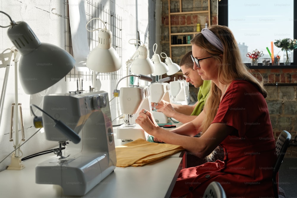 duas mulheres que trabalham em uma máquina de costura em uma loja