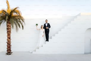 a bride and groom standing on a staircase next to a palm tree