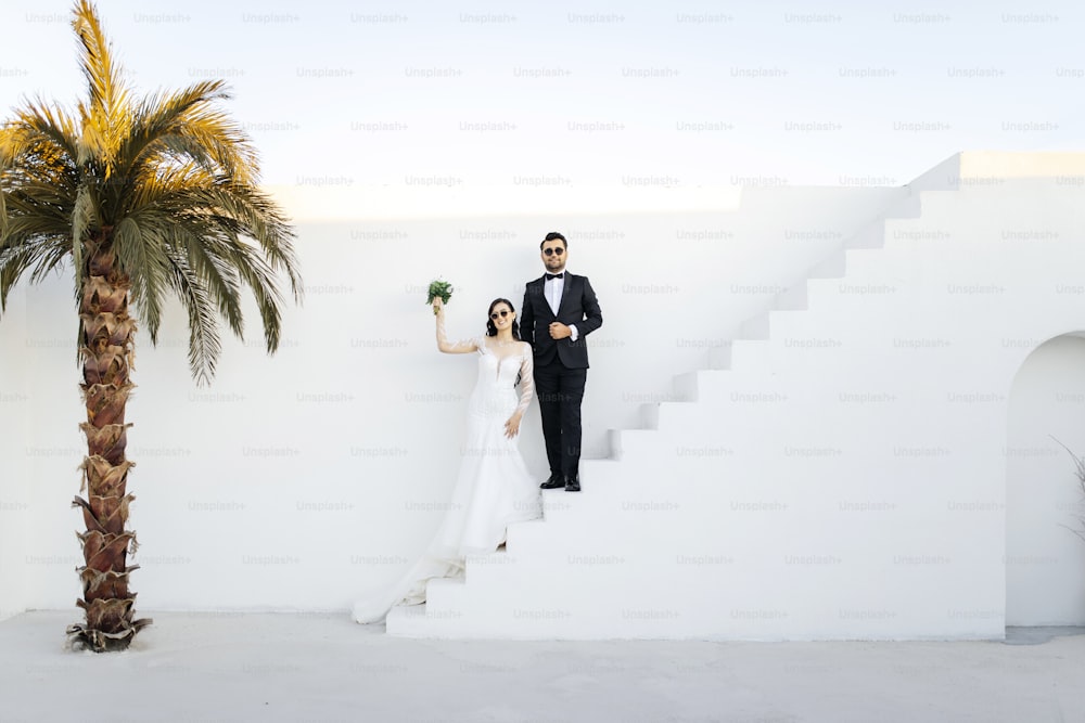 a bride and groom standing on a staircase next to a palm tree