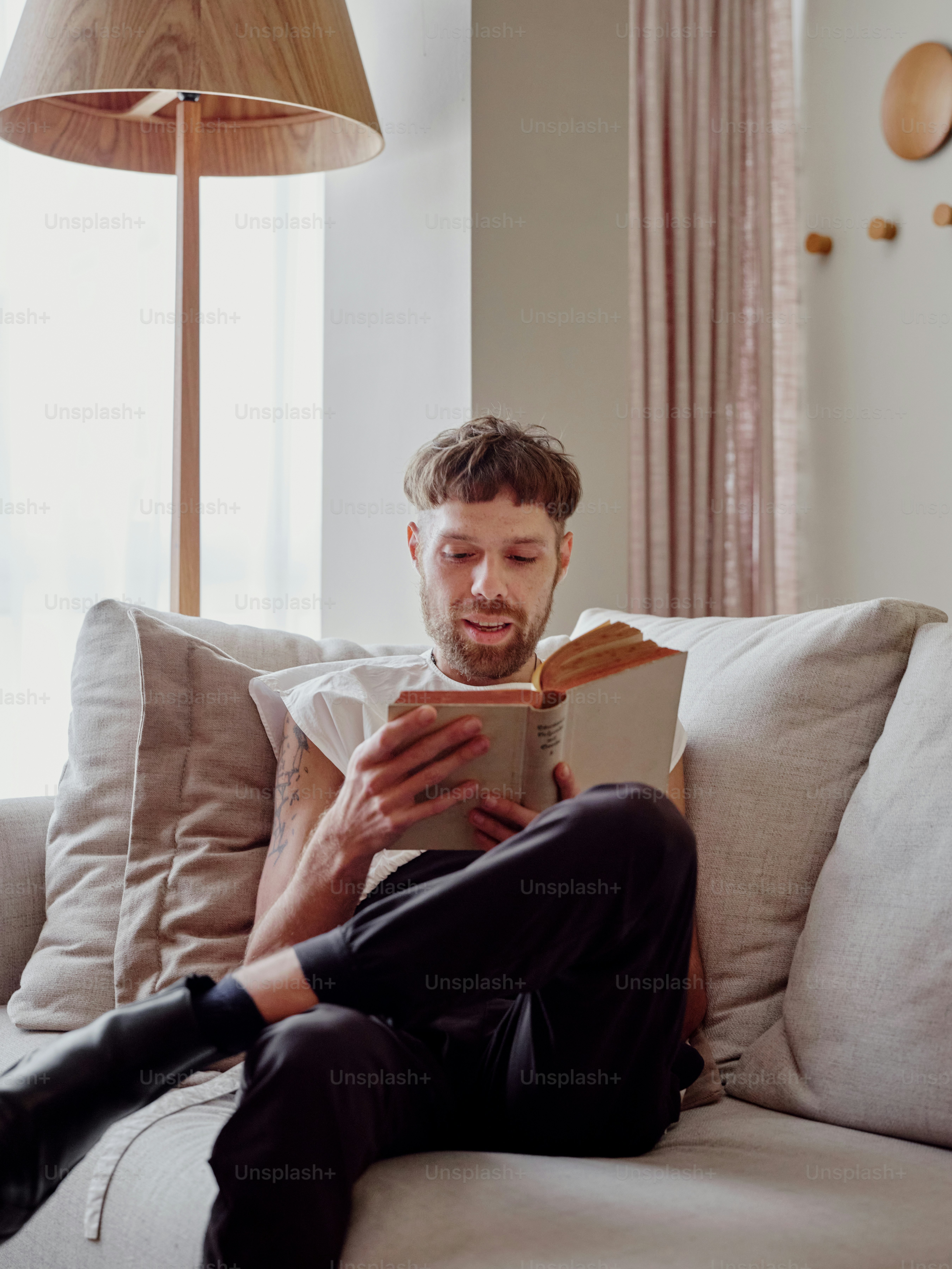Un hombre sentado en un sofá leyendo un libro