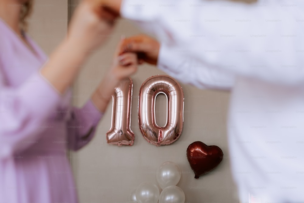 a woman putting a balloon in the shape of the number 10