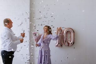 a man and a woman standing in front of a wall with confetti