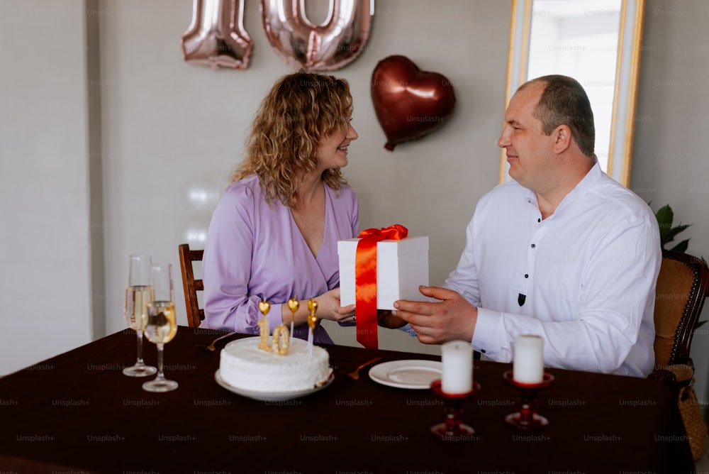 a man and woman sitting at a table with a cake