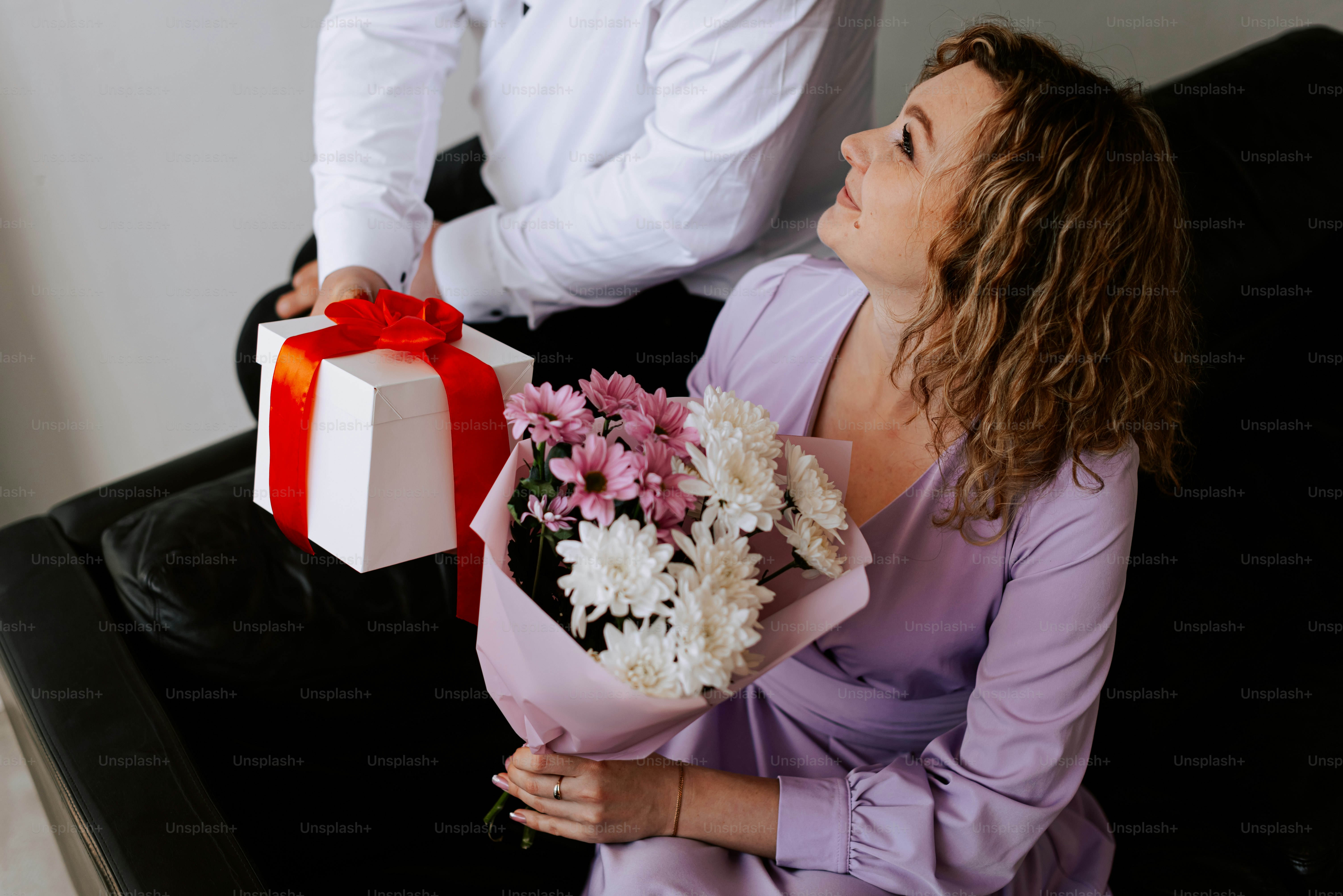 a woman sitting on a couch holding a bouquet of flowers
