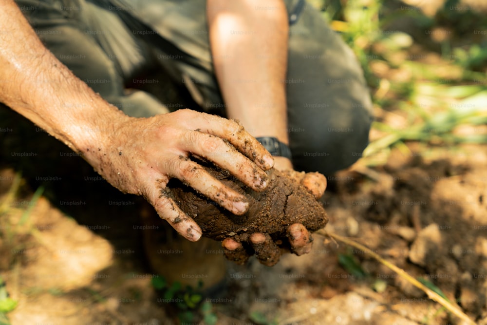 a man kneeling down holding a piece of dirt