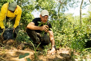 two men in yellow jackets crouching in the woods