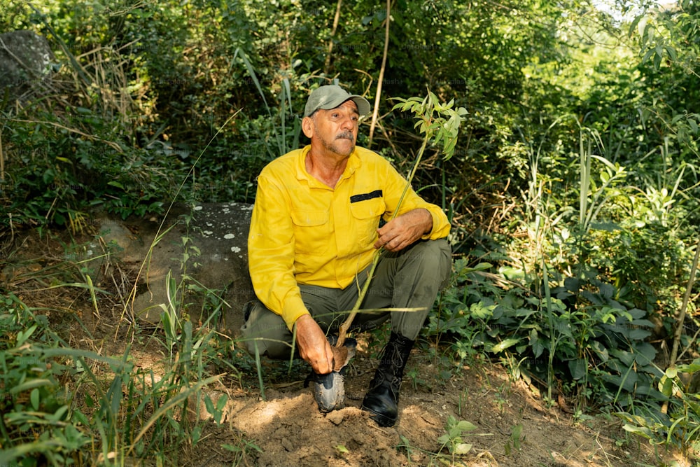 a man in a yellow shirt is sitting on a rock