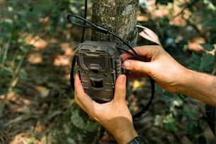 a person holding a radio next to a tree