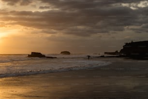 una persona in piedi su una spiaggia al tramonto
