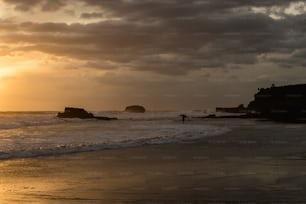 a person standing on a beach at sunset