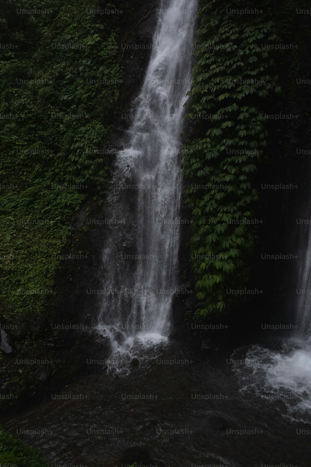 a waterfall with a man standing in front of it