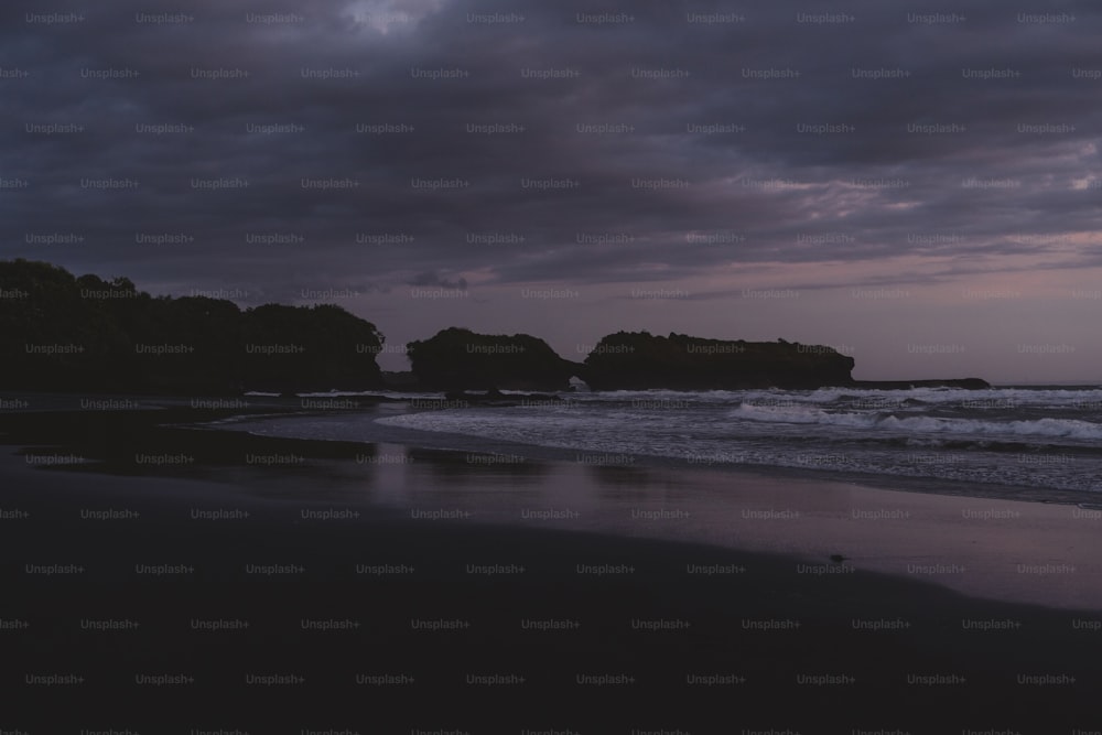un paio di rocce sedute in cima a una spiaggia vicino all'oceano