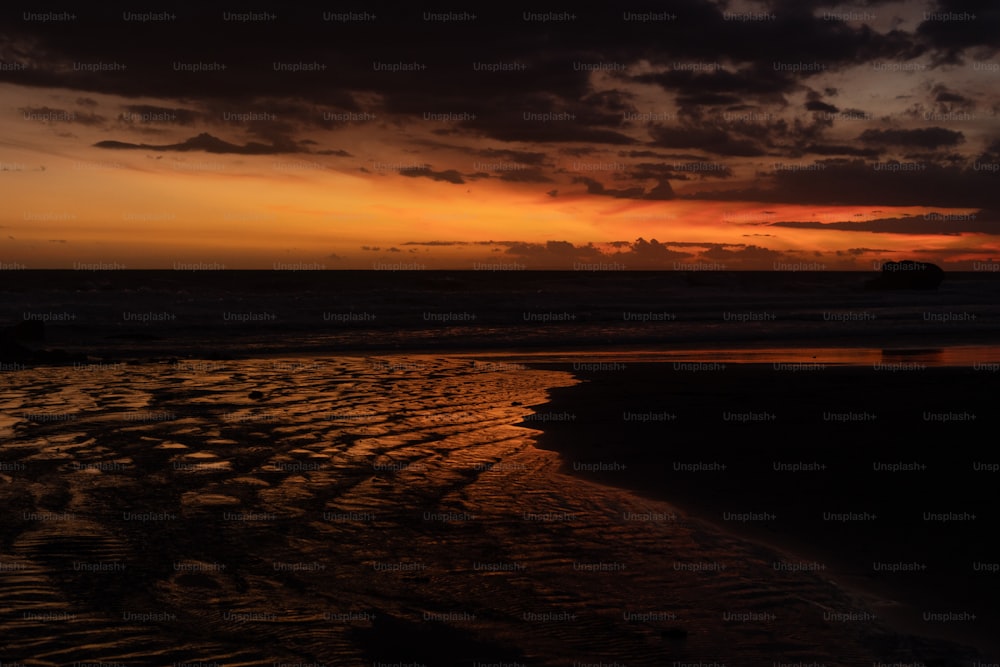 the sun is setting over the ocean on the beach