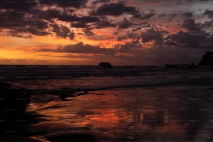 the sun is setting over the ocean on a cloudy day