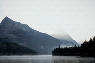 ein nebliger See mit einem Berg im Hintergrund