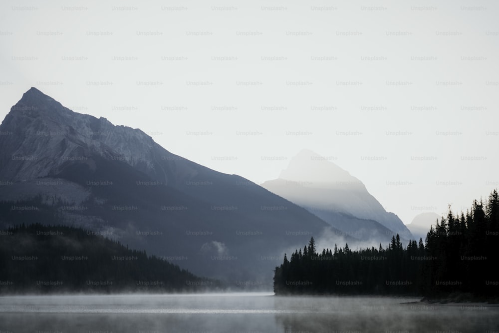 a foggy lake with a mountain in the background