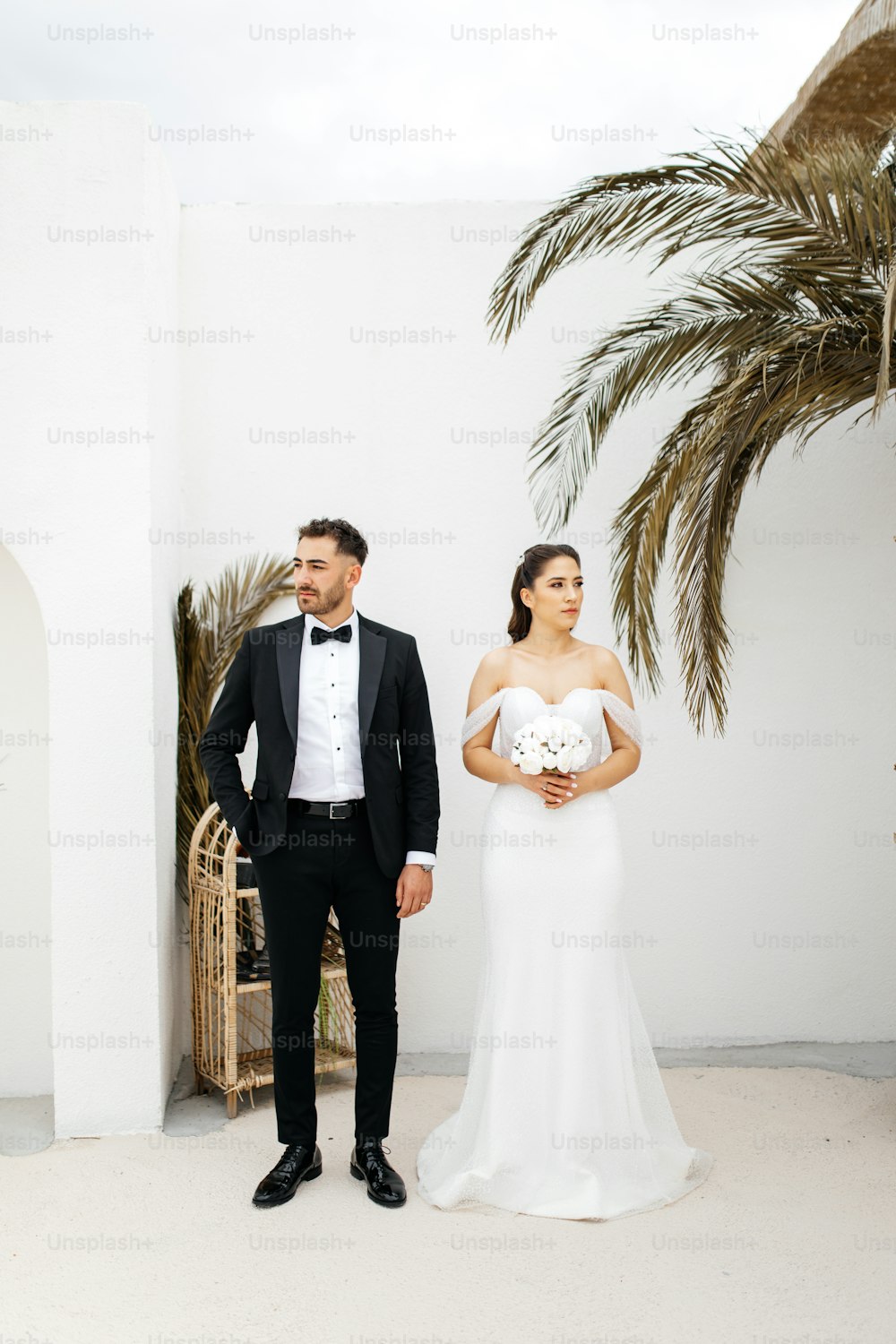a bride and groom standing in front of a palm tree