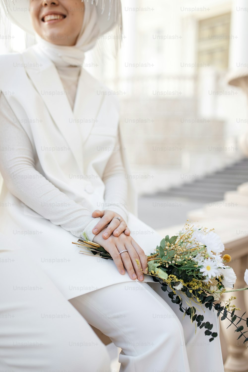 eine Frau in einem weißen Outfit und einem Blumenstrauß