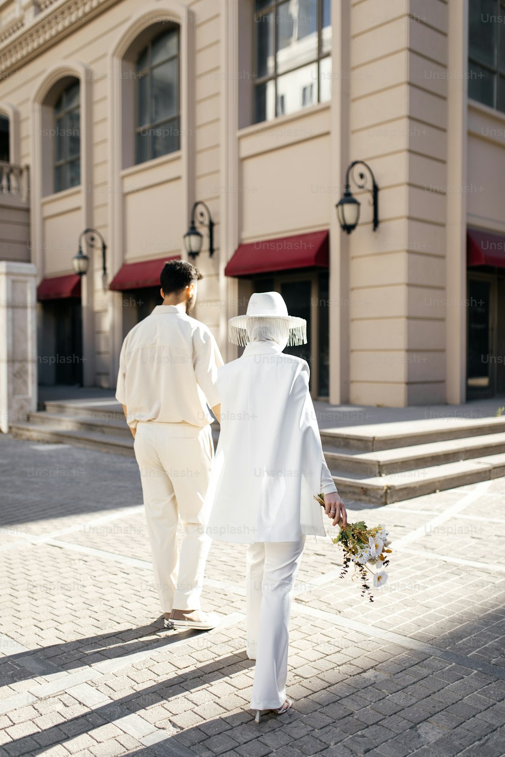 Ein Mann und eine Frau in Weiß gekleidet, die eine Straße entlang gehen