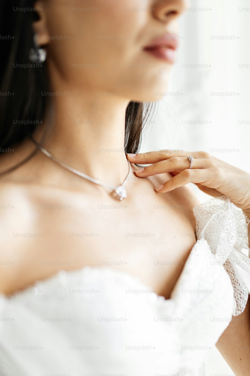 a woman in a wedding dress adjusting her necklace