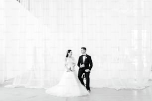 une mariée et un marié debout devant un rideau